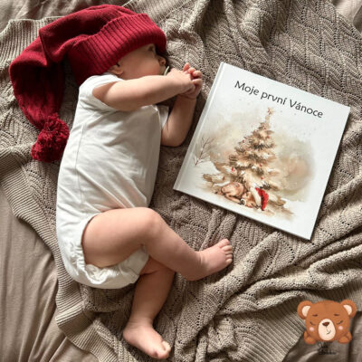 Miminko s vánoční čepičkou leží vedle autorského fotoalba Moje první Vánoce – vánoční vzpomínkové album pro miminka od Julie Vanhaber.