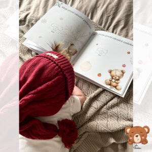 Miminko s červenou čepičkou si prohlíží otevřené vánoční album Moje první Vánoce s ilustracemi medvídků – originální české fotoalbum od Julie Vanhaber.