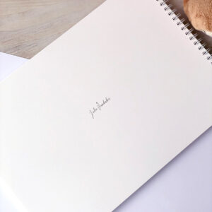 Detail zadní strany miminkovského alba s jemným logem Julie Vanhaber a kroužkovou vazbou.