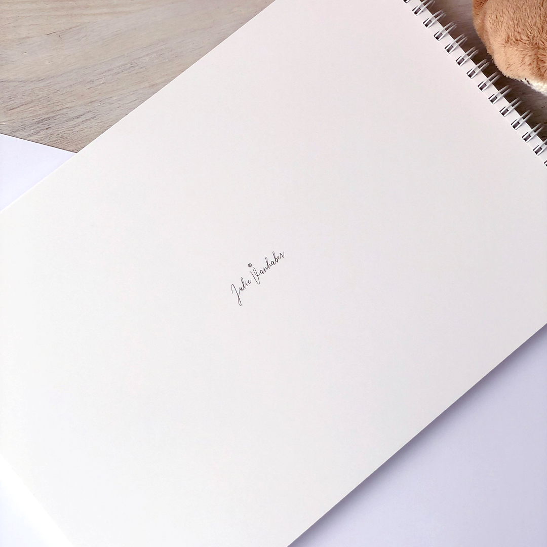 Detail zadní strany miminkovského alba s jemným logem Julie Vanhaber a kroužkovou vazbou.