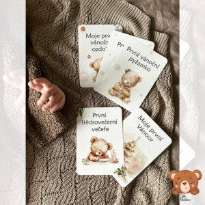 Miminko leží na hnědé dece vedle několika kartiček z kolekce Moje první Vánoce – ilustrace medvídků od Julie Vanhaber.